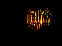 in a dark room a bamboo lantern is burning with a cozy light