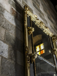 an old golden mirror with ornamentation at a stone wall of the grandmaster palace in rhodes city