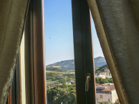 a room in the residenza ducale in bovino with golden curtains, a dark wooden window and the view in the lovely landscape in puglia
