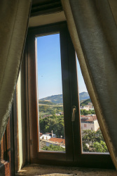 a room in the residenza ducale in bovino with golden curtains, a dark wooden window and the view in the lovely landscape in puglia