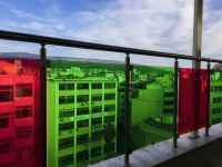 behind red and green glasses of a railing in the attalos hotel in athens you see the houses of the city