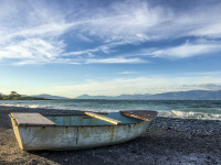 at the stony beach at the gulf of corinth is standing an old fisher boat
