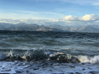 behind waves of the gulf of corinth you see the mountains near delphi, little wind turbines and some clouds at the sky