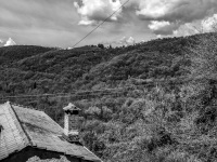 an old house in a hilly landscape and a bright sky with some clouds, black-and-white