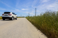 a white suv drives past grain fields on a country road