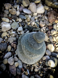 on a stone beach there is builded a little tower of grey stones