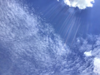 a blue sky with sun rays and with interesting clowds