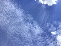 a blue sky with sun rays and with interesting clowds