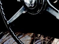 the black steering wheel and the brown leather seat of a rolls royce 25/30