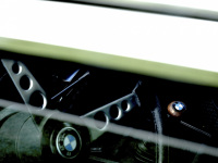 view through the open window of an oldtimer bmw e28 to the steering wheel and the gear stick