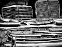 mercedes benz radiator grills and some chrome bumpers at a flea market, black-and-white