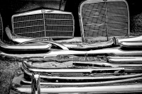 mercedes benz radiator grills and some chrome bumpers at a flea market, black-and-white