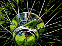 green grass ist reflecting in the chrome spoke rim of a jaguar