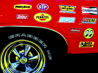 the rear tire of a red oldtimer with chrome rims and many stickers on the bodywork