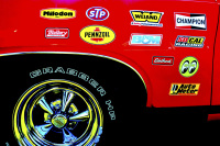 the rear tire of a red oldtimer with chrome rims and many stickers on the bodywork