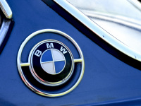 the emblem of bmw with chrome on a light blue oldtimer bmw