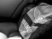 a pillow with lettering bentley is laying on the back seat of a bentley, black-and-white