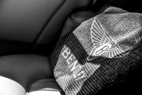 a pillow with lettering bentley is laying on the back seat of a bentley, black-and-white