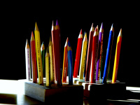 the sun is shining on many colored pencils where are standing in a little wooden stand