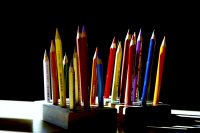 the sun is shining on many colored pencils where are standing in a little wooden stand