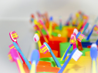 a lot of colorful children\'s toothbrushes are standing in also colorful toothbrush cups