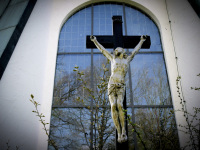 a cruzifix is standing in front of a church window by spring lihgt