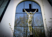 a cruzifix is standing in front of a church window by spring lihgt