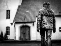 a woman figure in bronze is so placed like as she goes to the entrance of a church, black-and-white