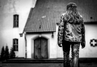 a woman figure in bronze is so placed like as she goes to the entrance of a church, black-and-white