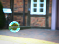 in front of a red half timbered house glides a little loveley soap bubble