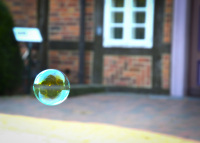 in front of a red half timbered house glides a little loveley soap bubble