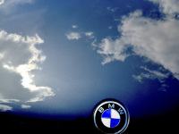 blue sky with white clodws is reflecting in a engine hood of an oldtimer bmw
