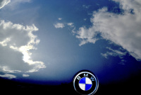blue sky with white clodws is reflecting in a engine hood of an oldtimer bmw