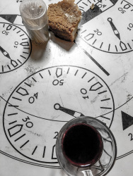 a peace of white bread, a glass of red wine and wooden toothpicks on a table painted with speetometers