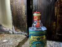 a bottle of eau de cologne 4711 is standing at an old wooden window on a stony windowsill