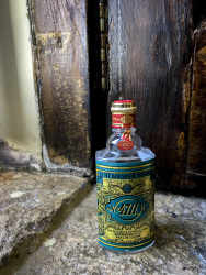 a bottle of eau de cologne 4711 is standing at an old wooden window on a stony windowsill