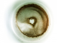 in a mint colored cup there is a coffee grounds that looks like a donut with a little heart inside