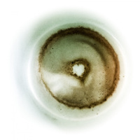 in a mint colored cup there is a coffee grounds that looks like a donut with a little heart inside