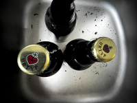 three bottles of astra pilsener are standing in a stainless steel sink