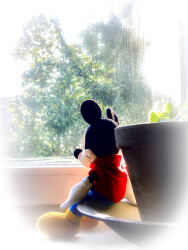 a mickey mouse puppet is sitting at a window and looks outside
