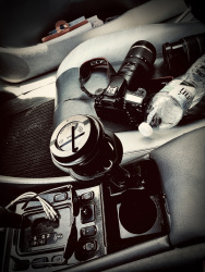 a camera, a lens, a bottle water and a cup of coffee on the passenger seat in a mercedes clk