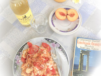 a meal on a plate, a peach, a bottle of retsina with a glass and the book reflections of a marine venus from lawrence durrell