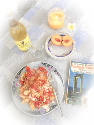 a meal on a plate, a peach, a bottle of retsina with a glass and the book reflections of a marine venus from lawrence durrell