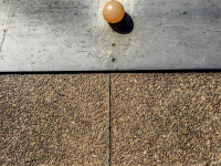 a silver metal plate on a light red stone floor and a light orange mini golf ball