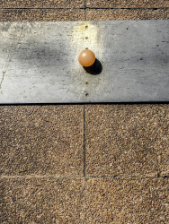 a silver metal plate on a light red stone floor and a light orange mini golf ball