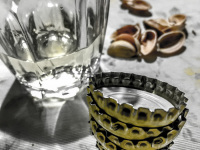empty pistachio shells, a half full glass of cair retsina and some bottle caps
