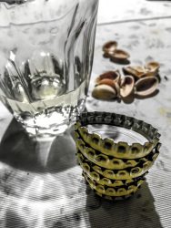 empty pistachio shells, a half full glass of cair retsina and some bottle caps
