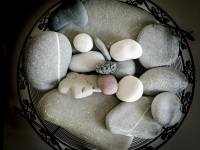 big and small grey and white stones in a black round metall bowl
