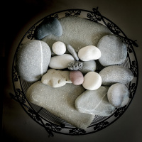big and small grey and white stones in a black round metall bowl