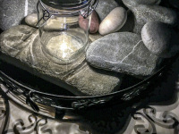 a solar lantern, some big and small stones, shadows and a black metall bowl